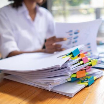 businesswoman-hands-working-on-stacks-of-paper-documents-to-search-and-review-documents-piled-on-table-before-sending-them-to-board-of-directors-to-use-correct-documents-in-meeting-with-businessman-photo